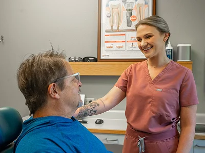 Smiling dental assistant greeting a patient in the treatment chair