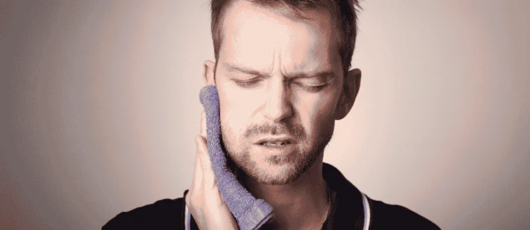 Man pressing a cold compress against his jaw