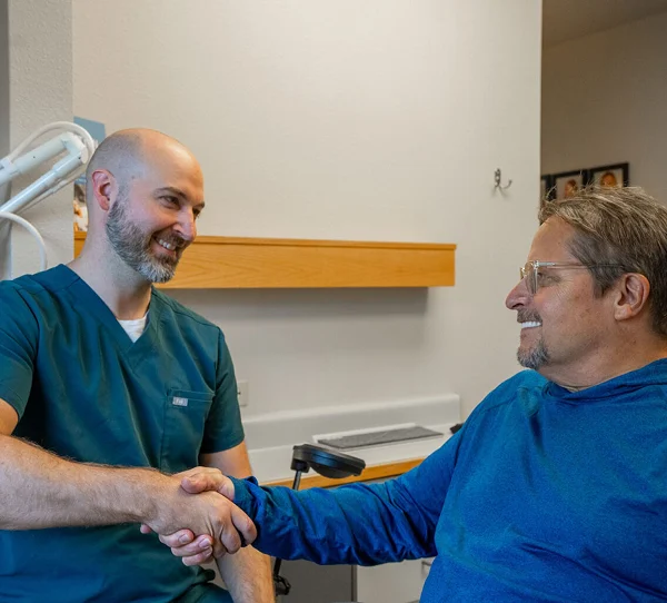 Dentist greeting a patient with a handshake beside the treatment chair