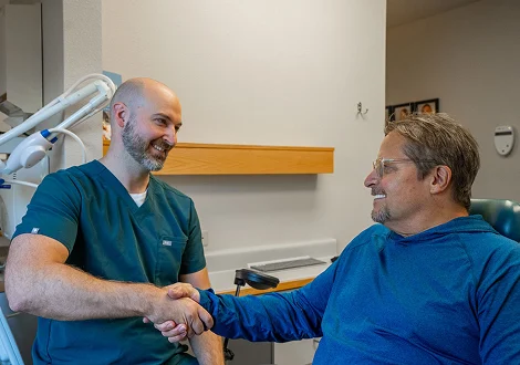 Dentist shaking hands with a patient in a treatment room