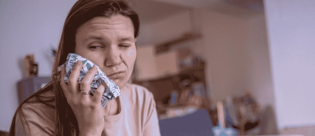 Woman holding an ice pack to her cheek